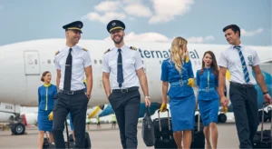 Pilotos y tripulantes de cabina caminando sonrientes frente a un avión comercial, representando la experiencia profesional alcanzada tras completar la formación en GTA