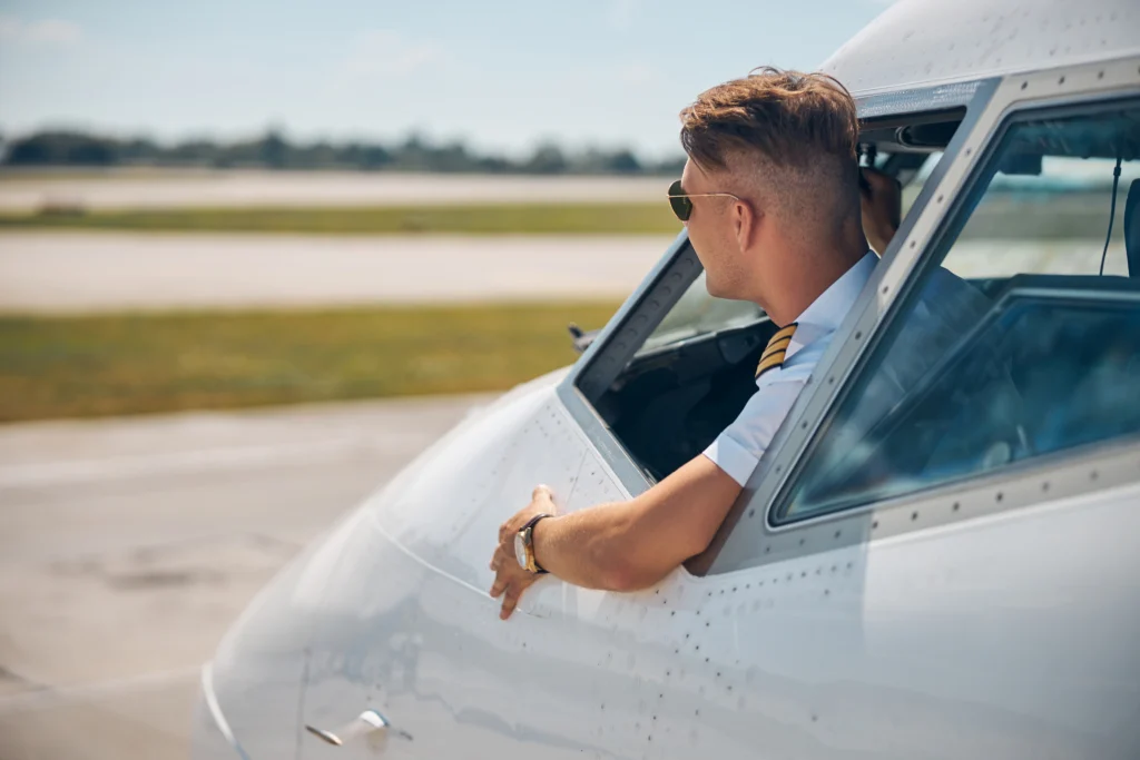 Young pilot looking out from aircraft cockpit window before takeoff